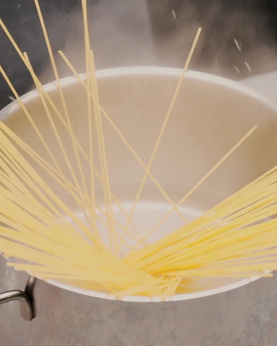 A spoonful of soft, roasted garlic paste being dropped into a black pan.