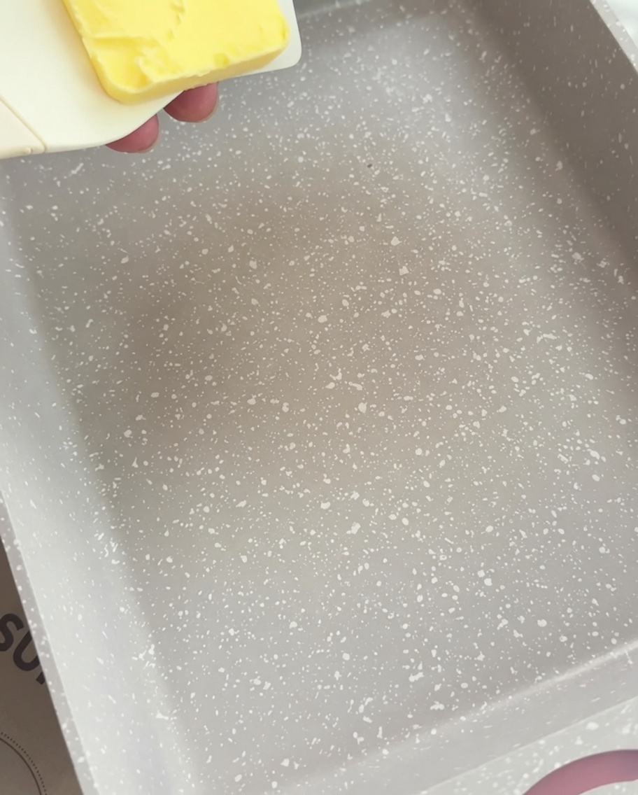 A rectangular pan with a pat of yellow butter beginning to melt into a liquid state.