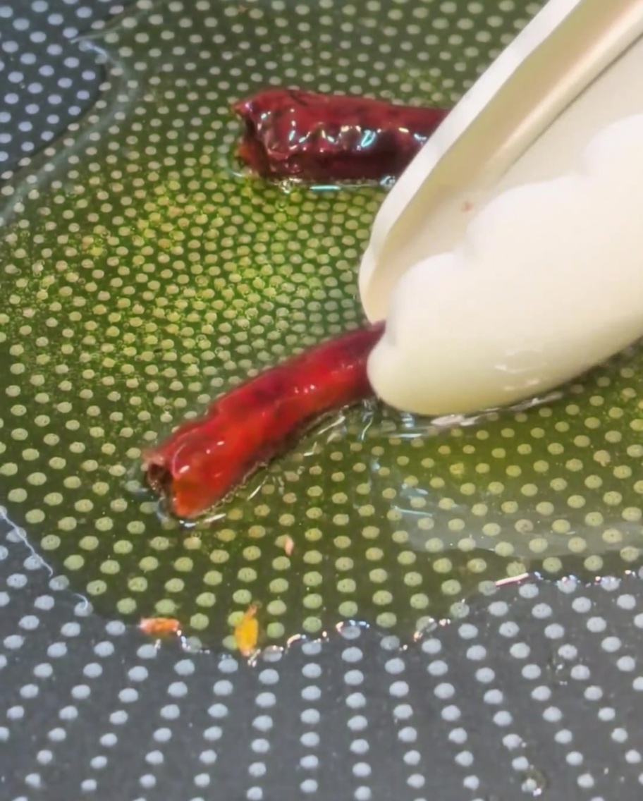 Dried red chilies being added to the hot, garlic-infused olive oil.