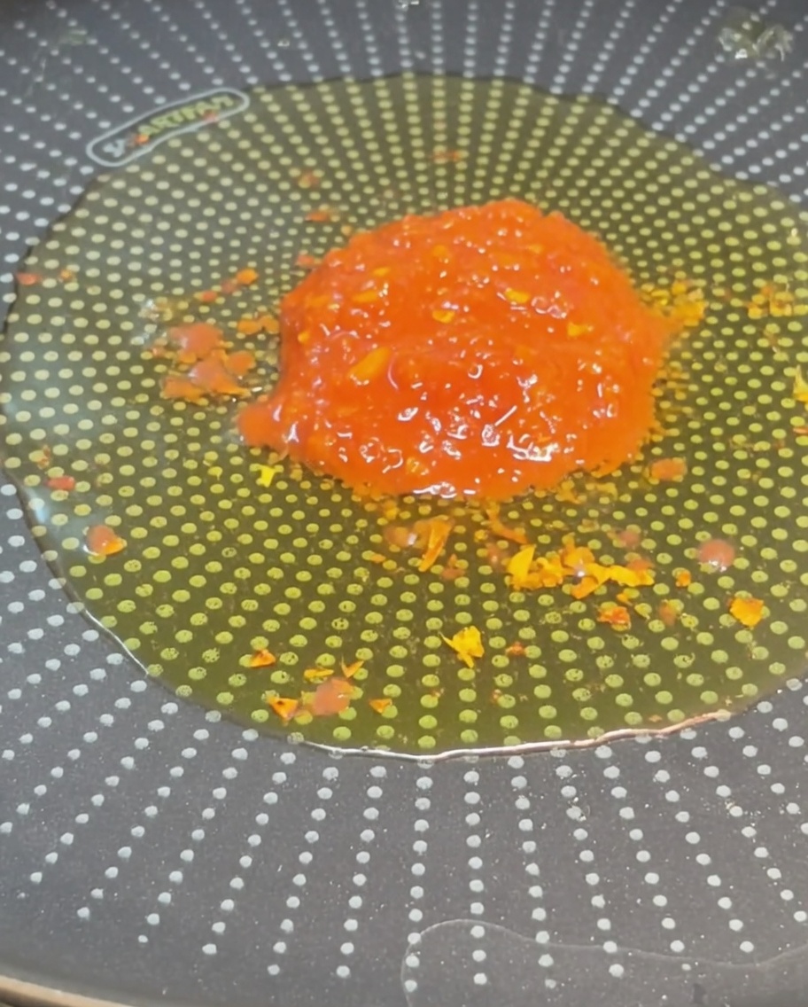 A heap of bright red chunky diced tomatoes sitting in the center of a pan filled with seasoned olive oil.