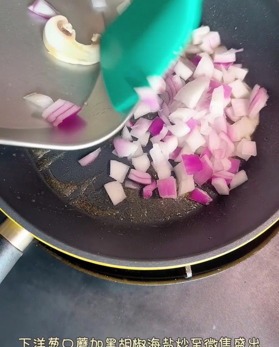Diced red onion and sliced mushrooms sautéing in a pan, lightly seasoned with pepper and salt.