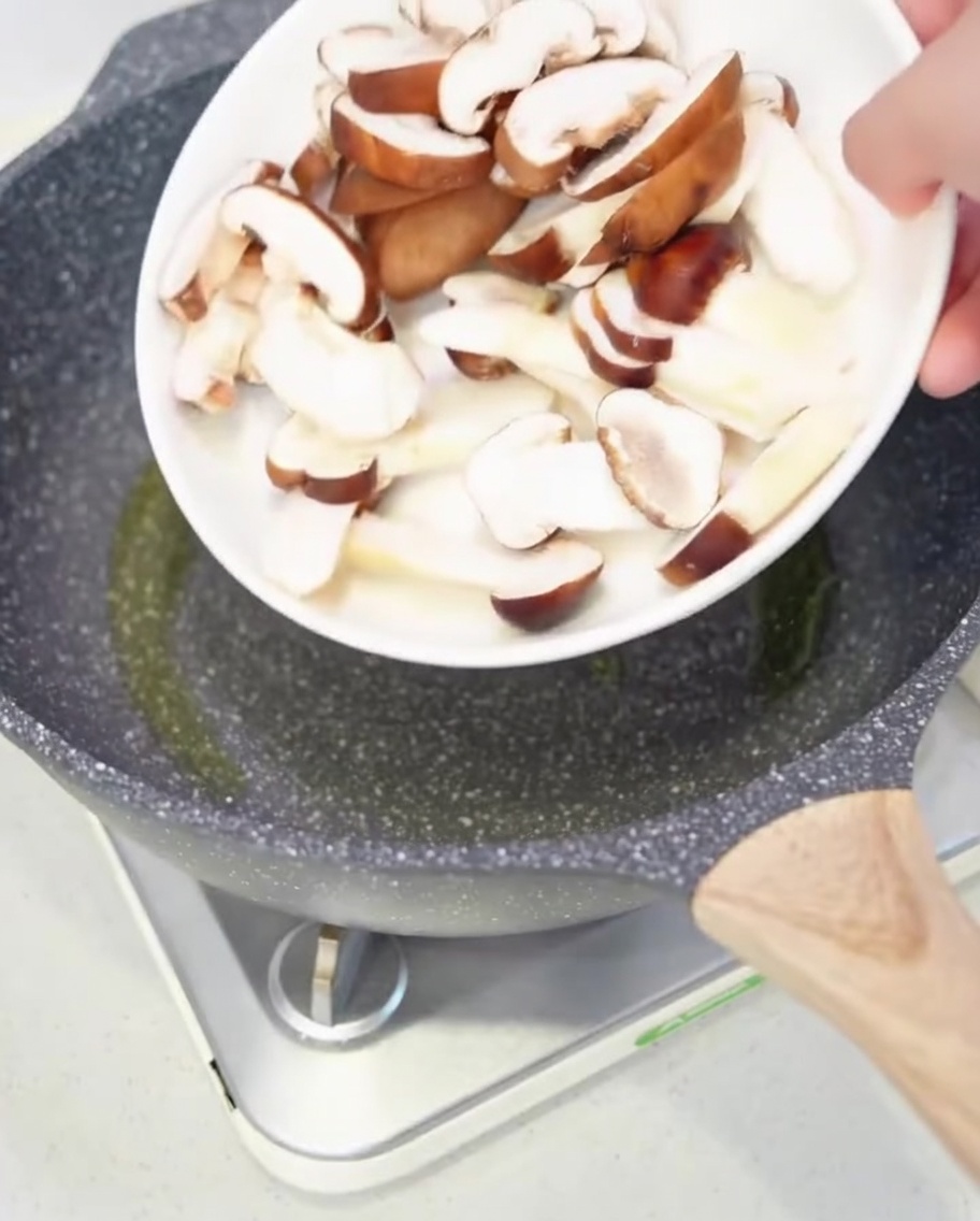 Mixed mushrooms sizzling in a pan with olive oil.