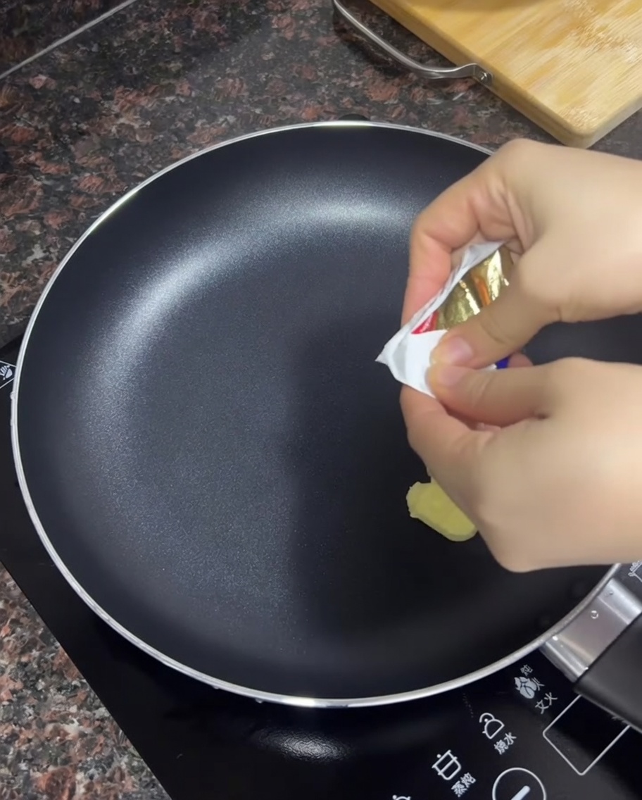 Butter melting in a hot black non-stick skillet.