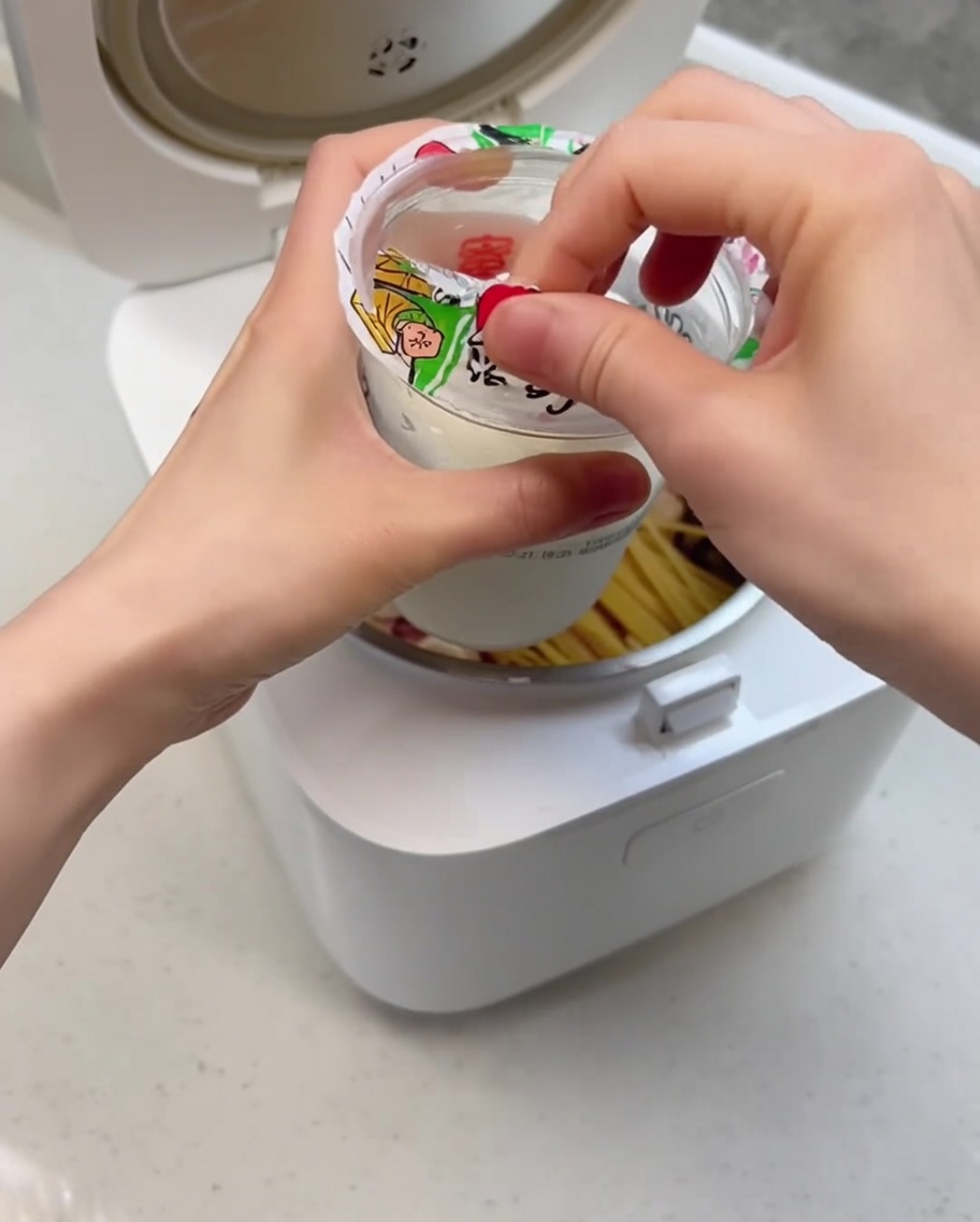 A close-up shot showing the creamy sundae being poured into the rice cooker pot over the ingredients.