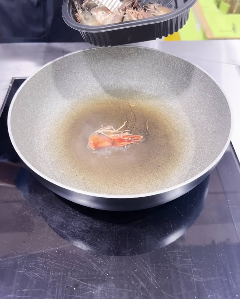 Shrimp heads being sautéed in a pan to create a flavorful shrimp-infused oil.