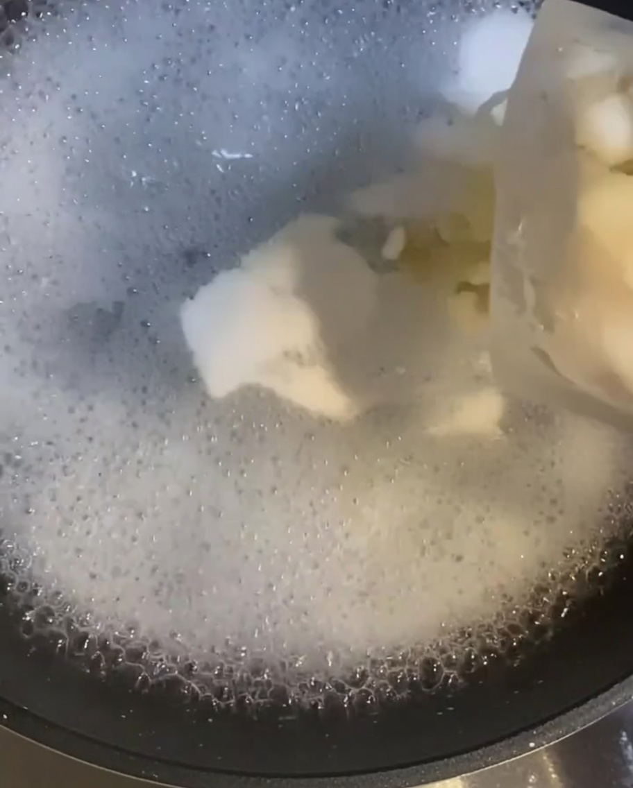 Raw shrimp being added to a pot of boiling water, appearing as they begin to cook.