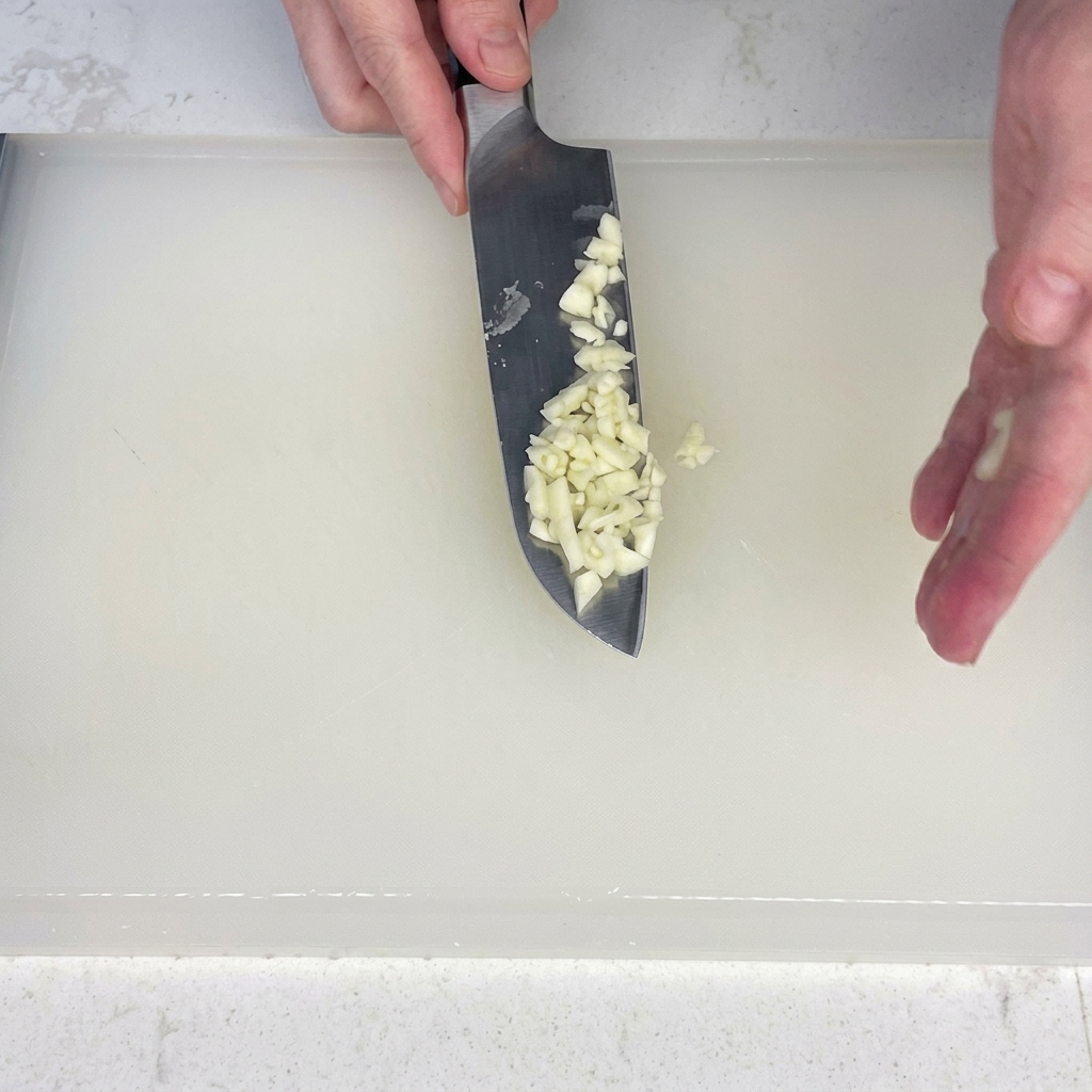 Bacon slices being cut into small pieces on a cutting board.