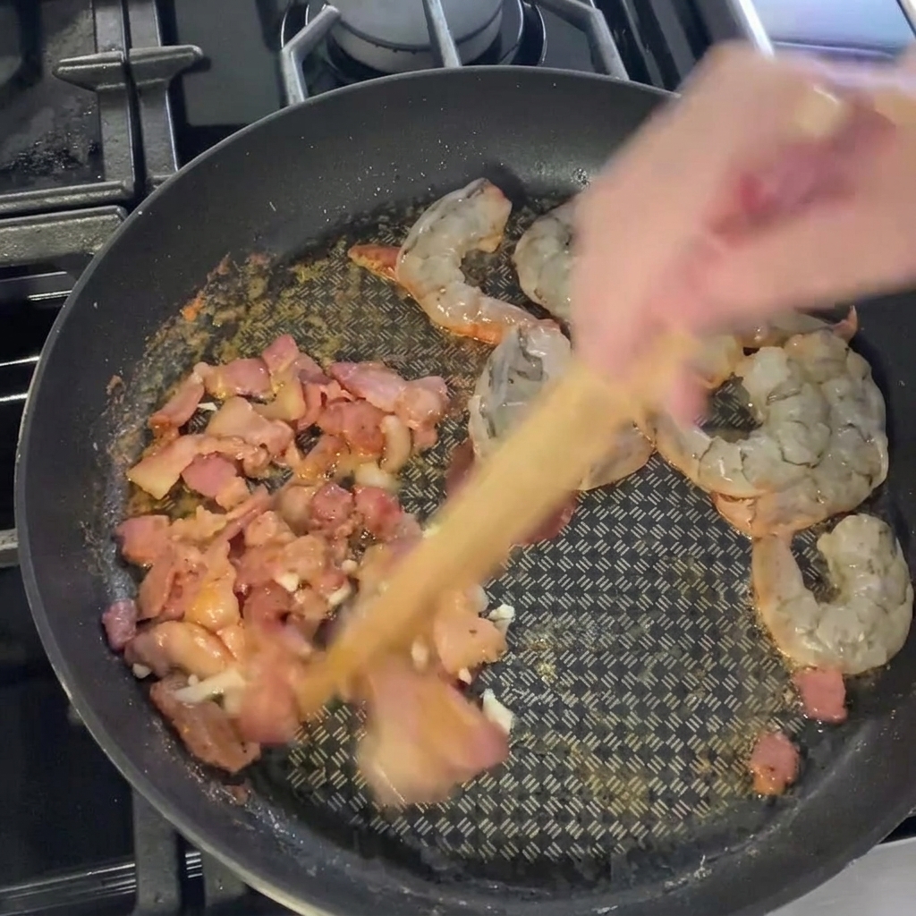 Fresh green asparagus segments being added to the pan with the other ingredients.