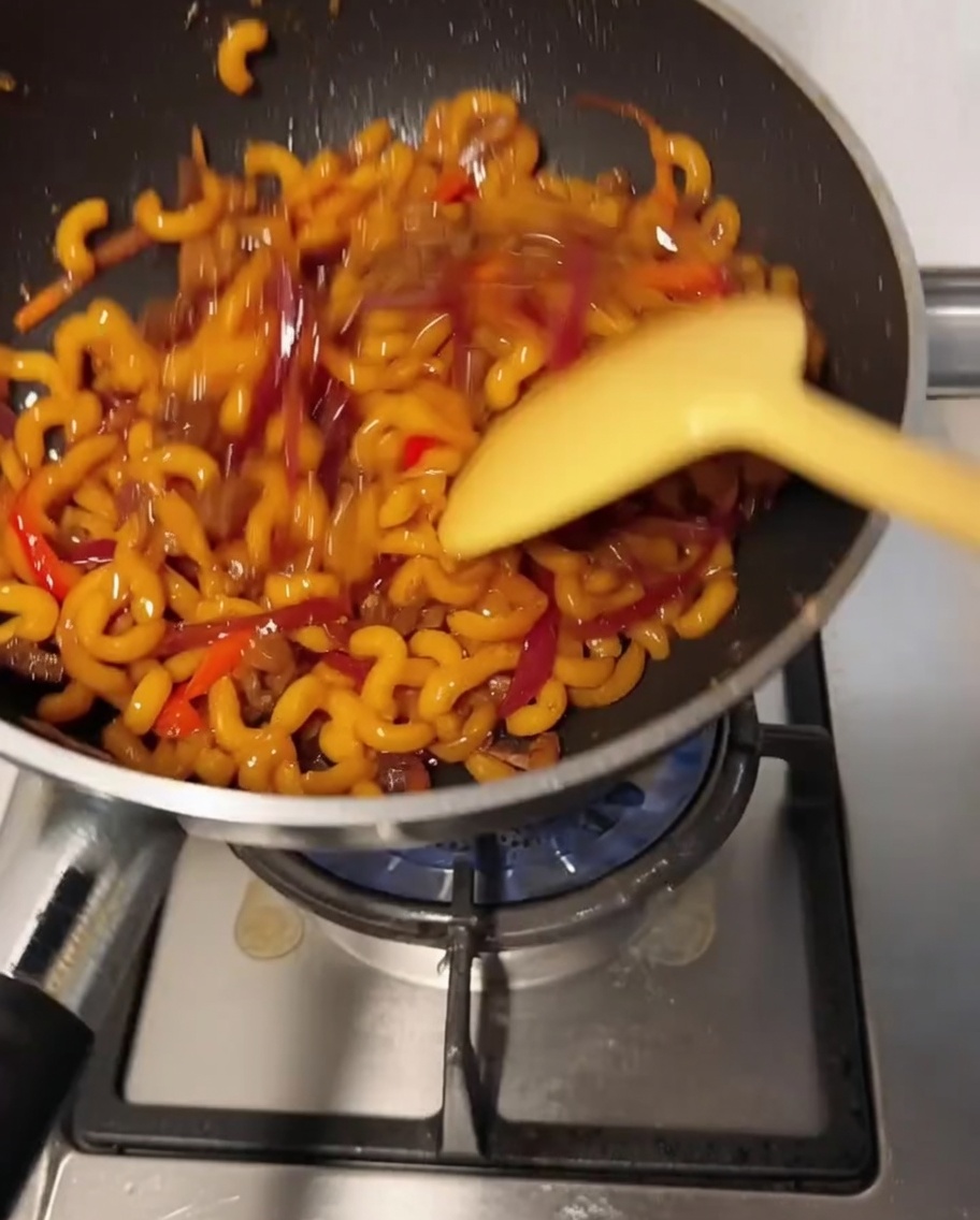 The macaroni mixture being stirred in the wok as the cheese melts and coats the ingredients.