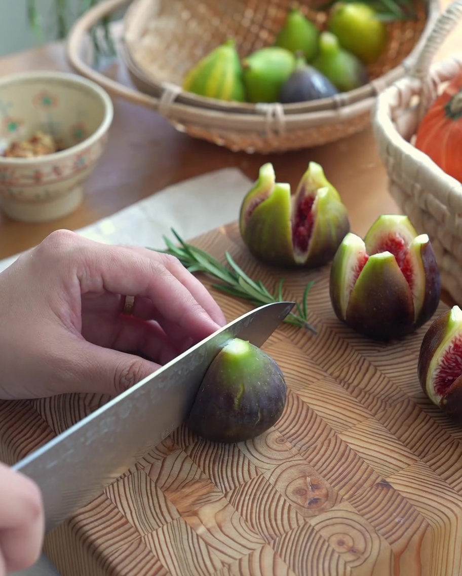 Fresh figs with a cross-cut opening on a wooden cutting board, ready for stuffing.