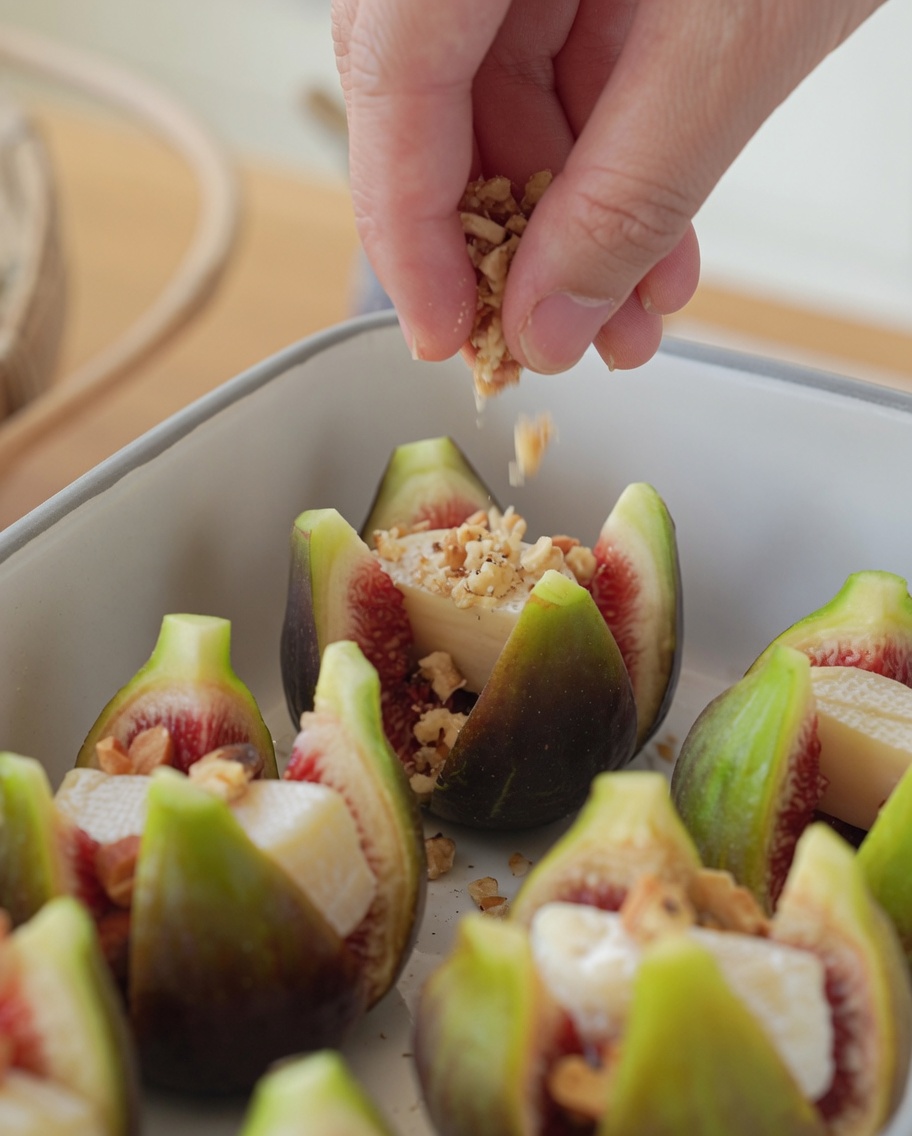 Stuffed figs in a baking dish topped with a sprinkling of crushed nuts.