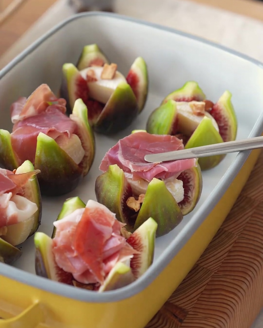 Stuffed figs topped with ham slices and fresh sprigs of rosemary.