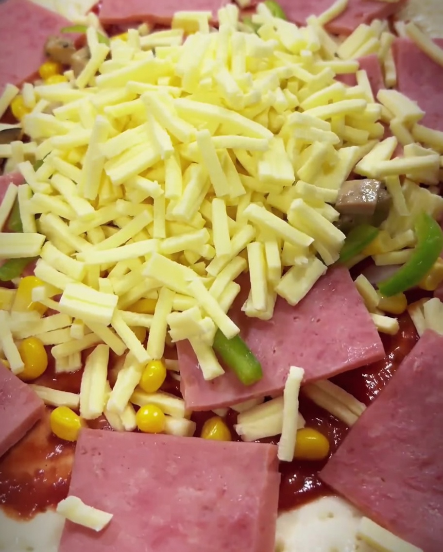 The assembled pizza being placed inside a hot oven to begin the baking process.
