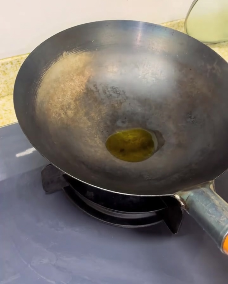 Chopped tomatoes cooking in a hot wok, showing steam and reduced liquid.