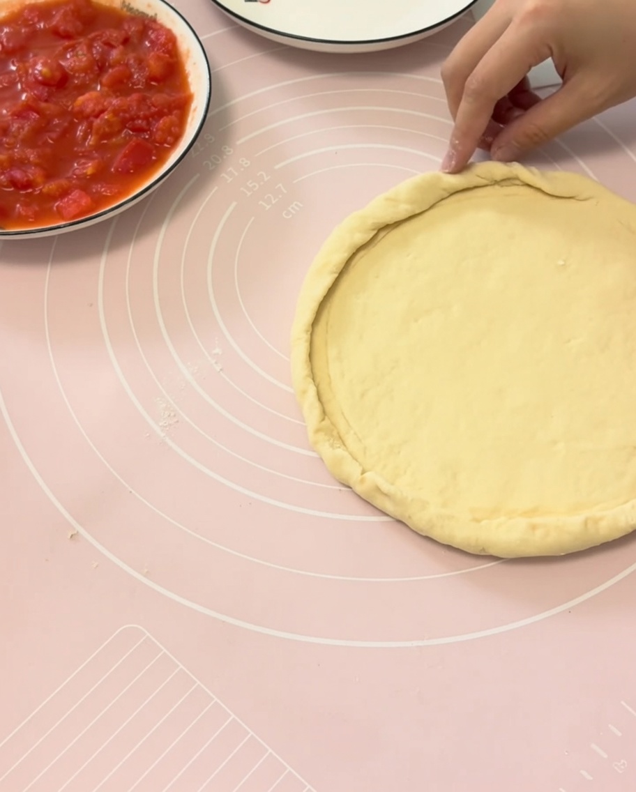 Hands folding the edges of pizza dough over a plate to form a perfect crust.