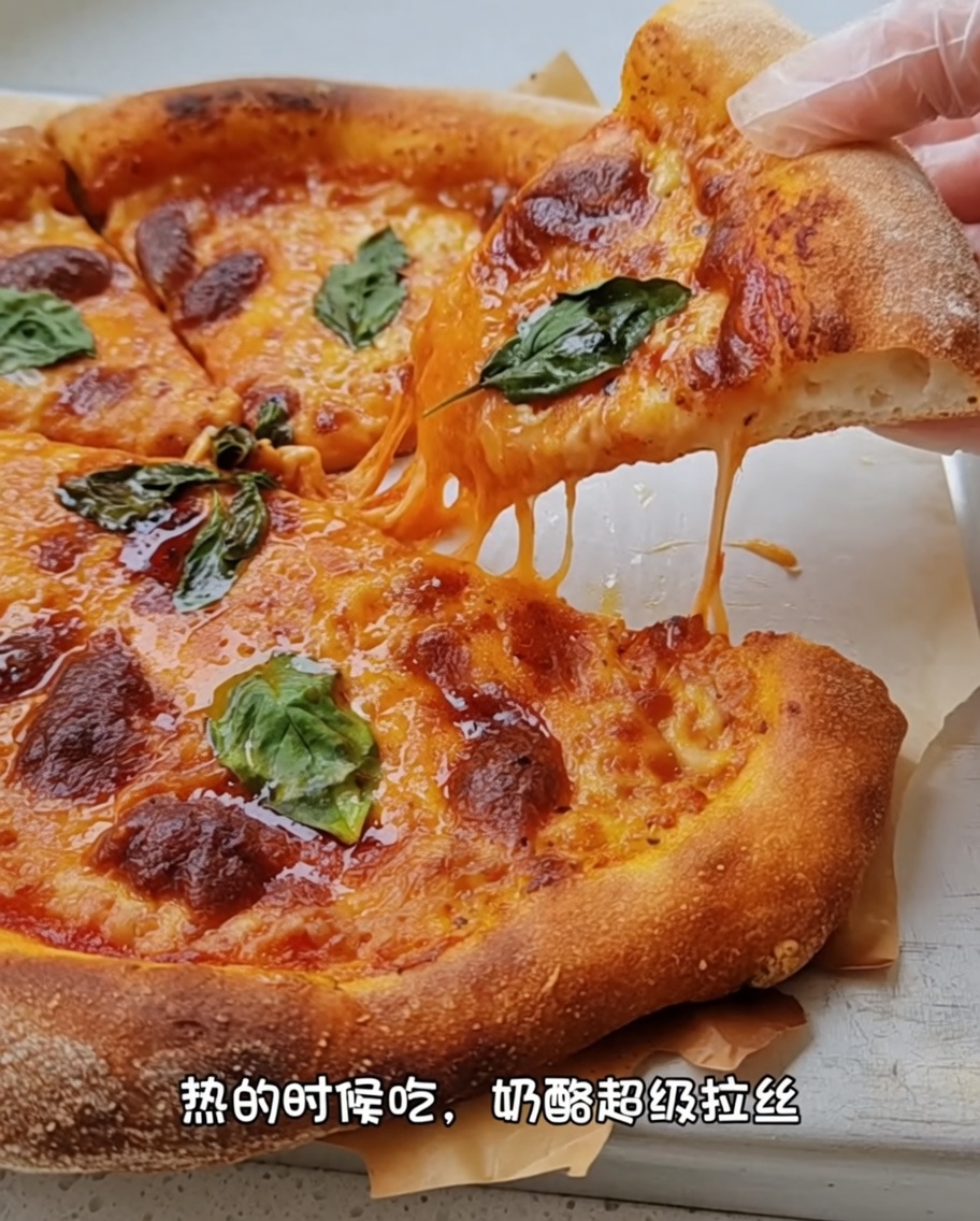 Hands using knuckles to stretch a round pizza dough base on a floured surface.