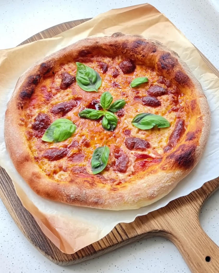 Italian tomato sauce being spread evenly over a round pizza dough base.