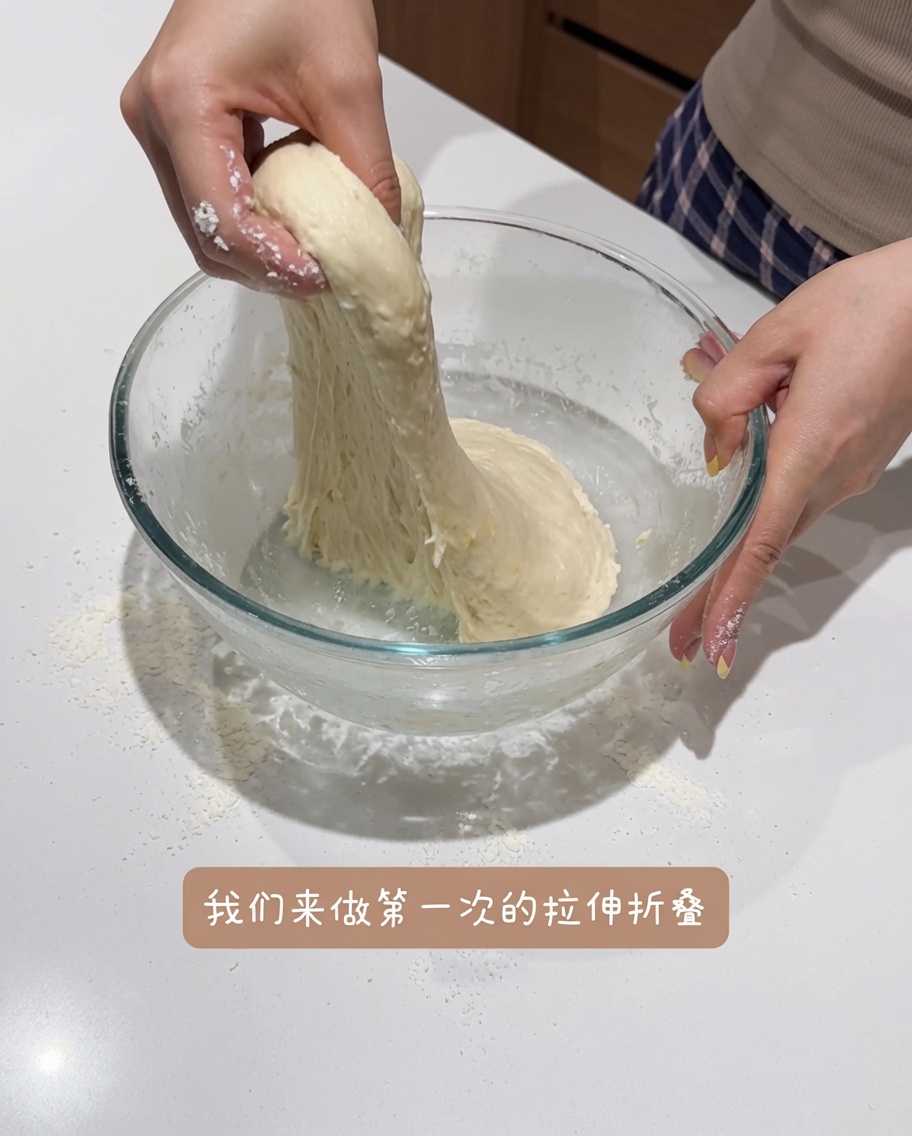 The dough being stretched and folded inside the bowl to improve its structure.