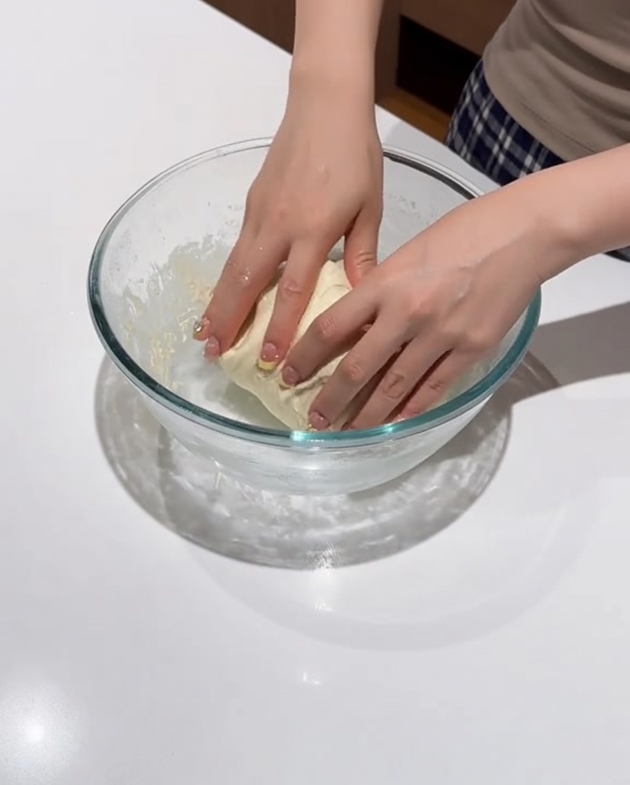 A smooth, rounded ball of dough resting in the bowl.