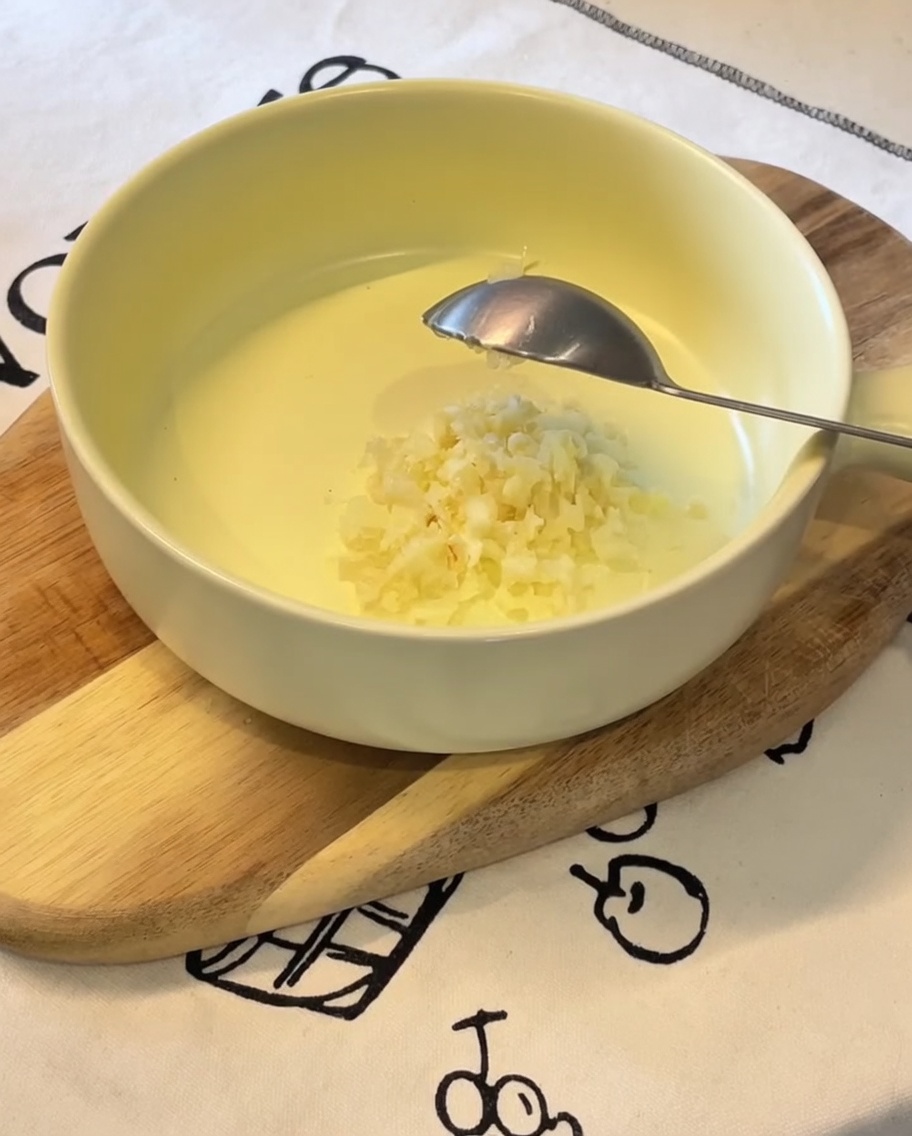 Minced garlic, sliced green onions, Japanese mayonnaise, an egg yolk, and ramen seasoning powder sitting in a yellow bowl.