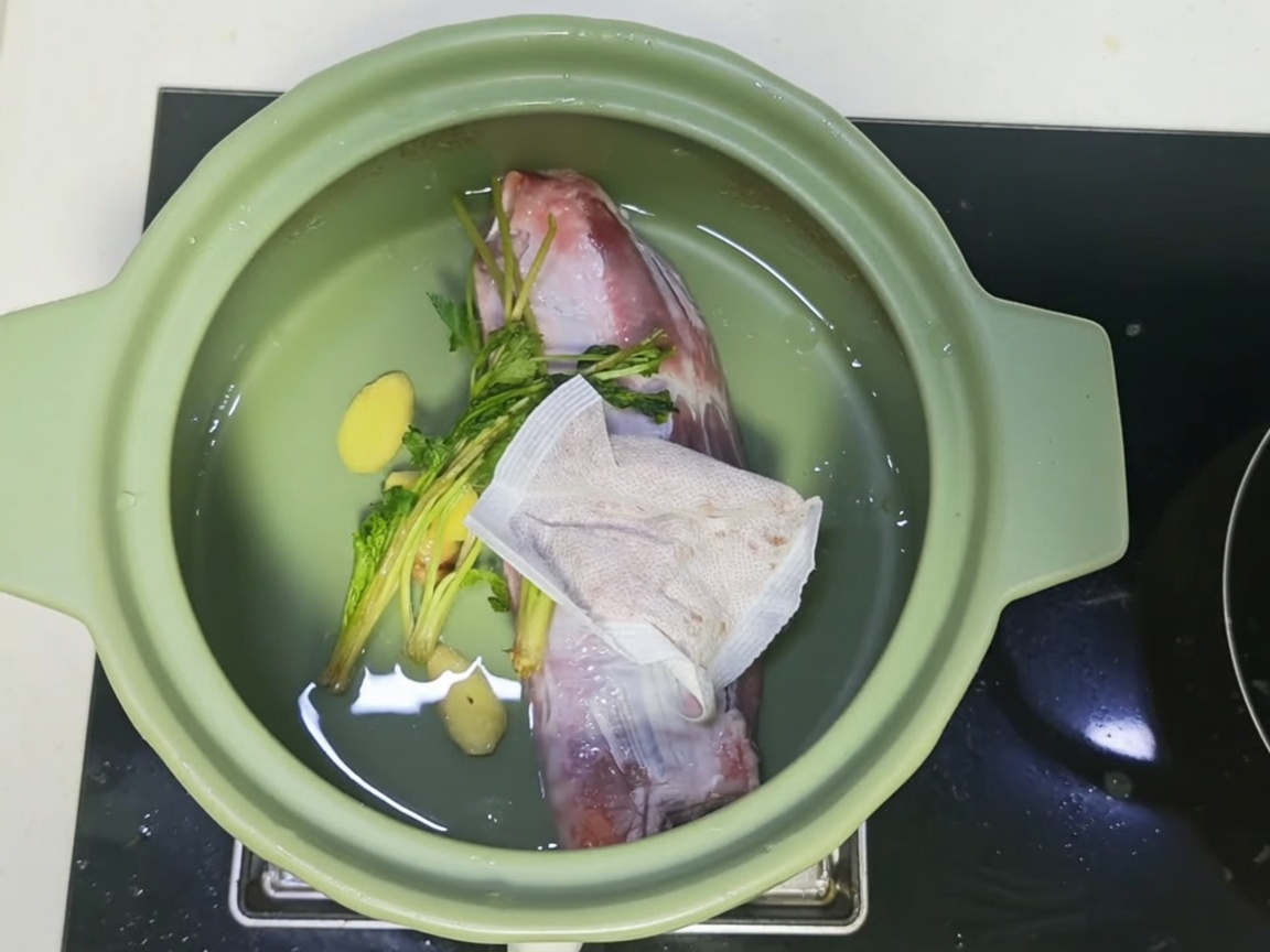 A clay pot filled with beef, spices, and a dark, savory broth mixture.