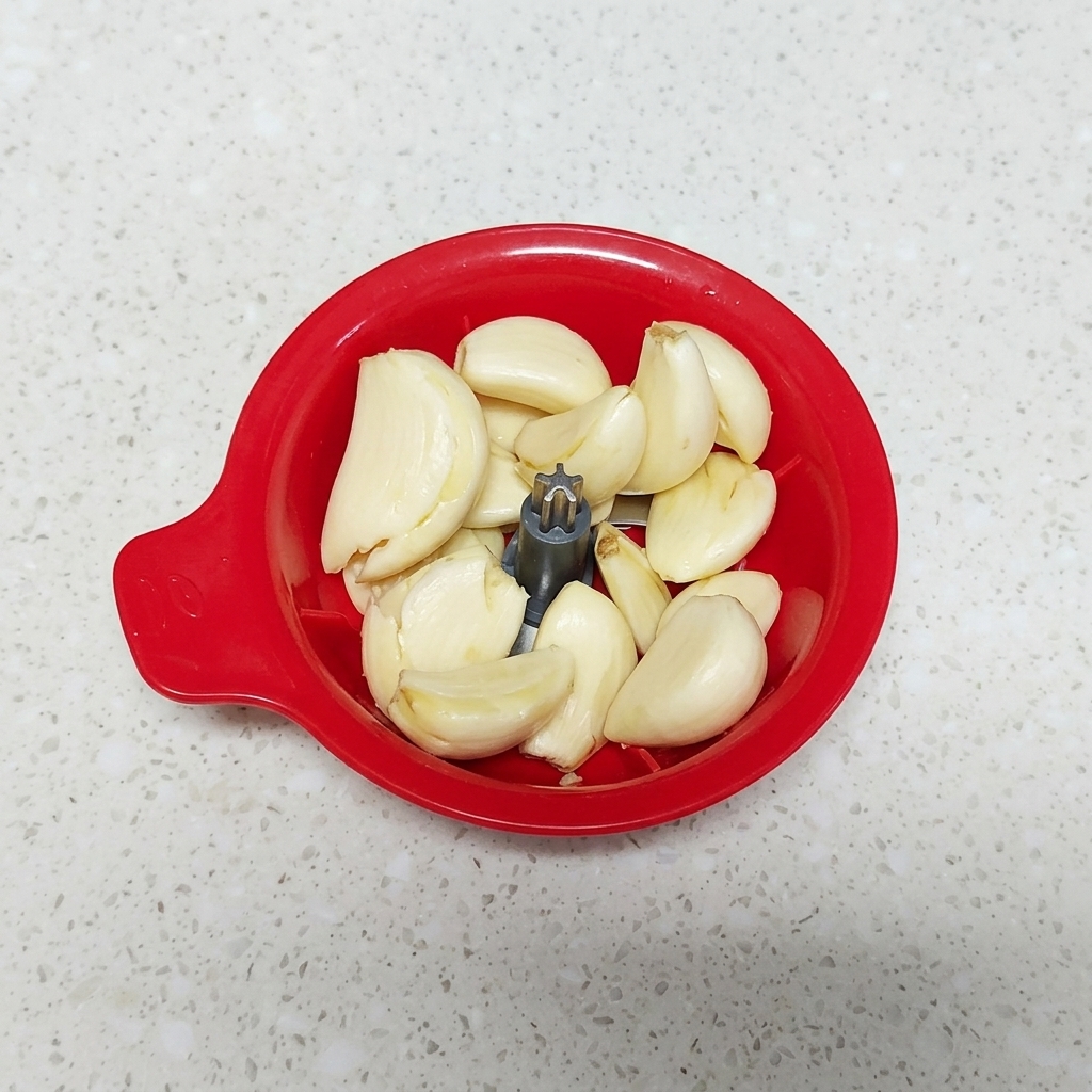 Garlic cloves inside a small manual food chopper.