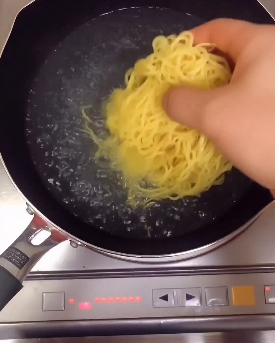 Yellow ramen noodles boiling in a pot of water on the stove.