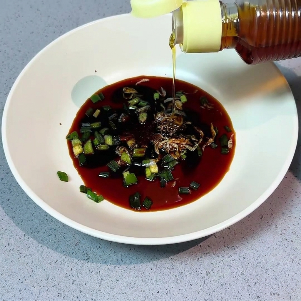 Sesame oil being poured from a bottle into a bowl with various seasonings.