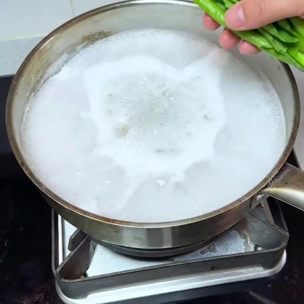 Fresh bok choy being added to a pot of boiling water.
