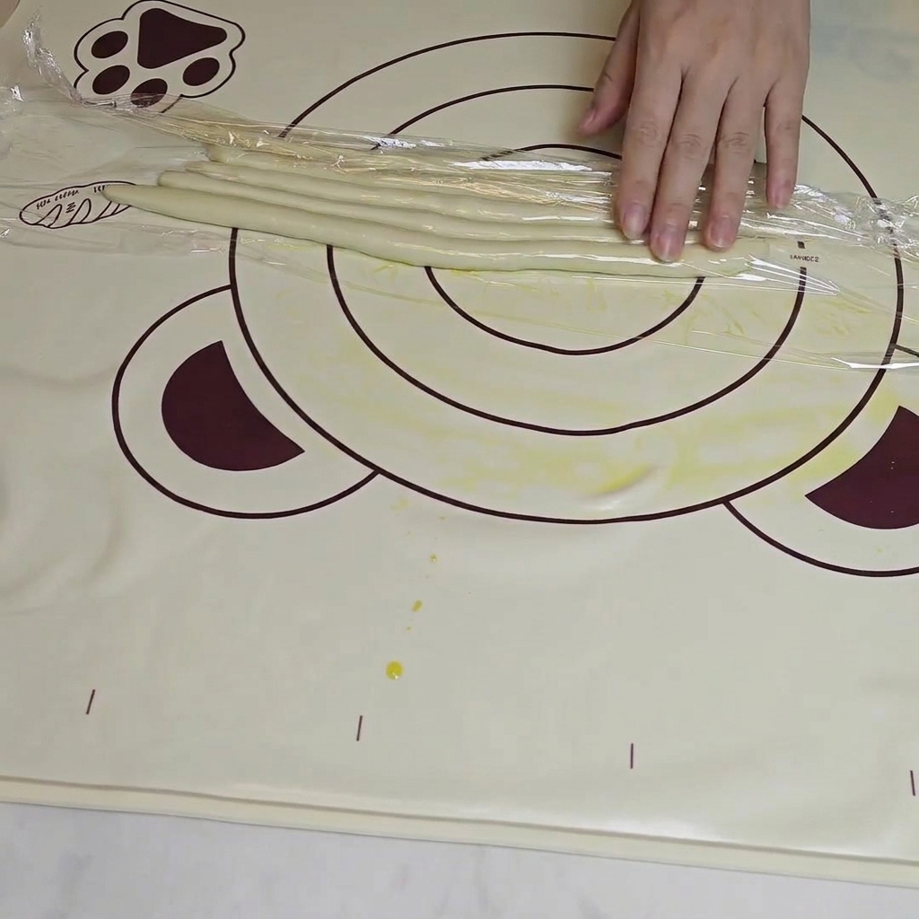 Hands folding and pulling long, thin dough strands to achieve the desired noodle length and texture.