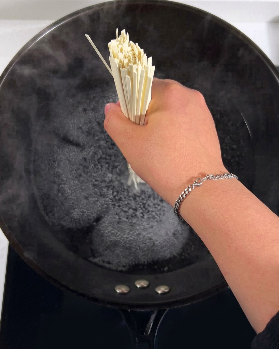 Noodles submerged in boiling water in a large pot.
