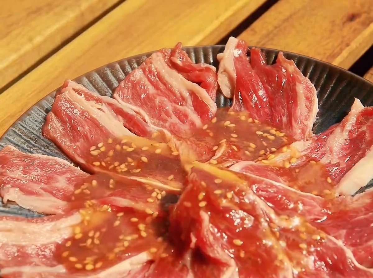 Thin slices of raw beef arranged in a shallow dish, coated in the prepared Yakiniku sauce.