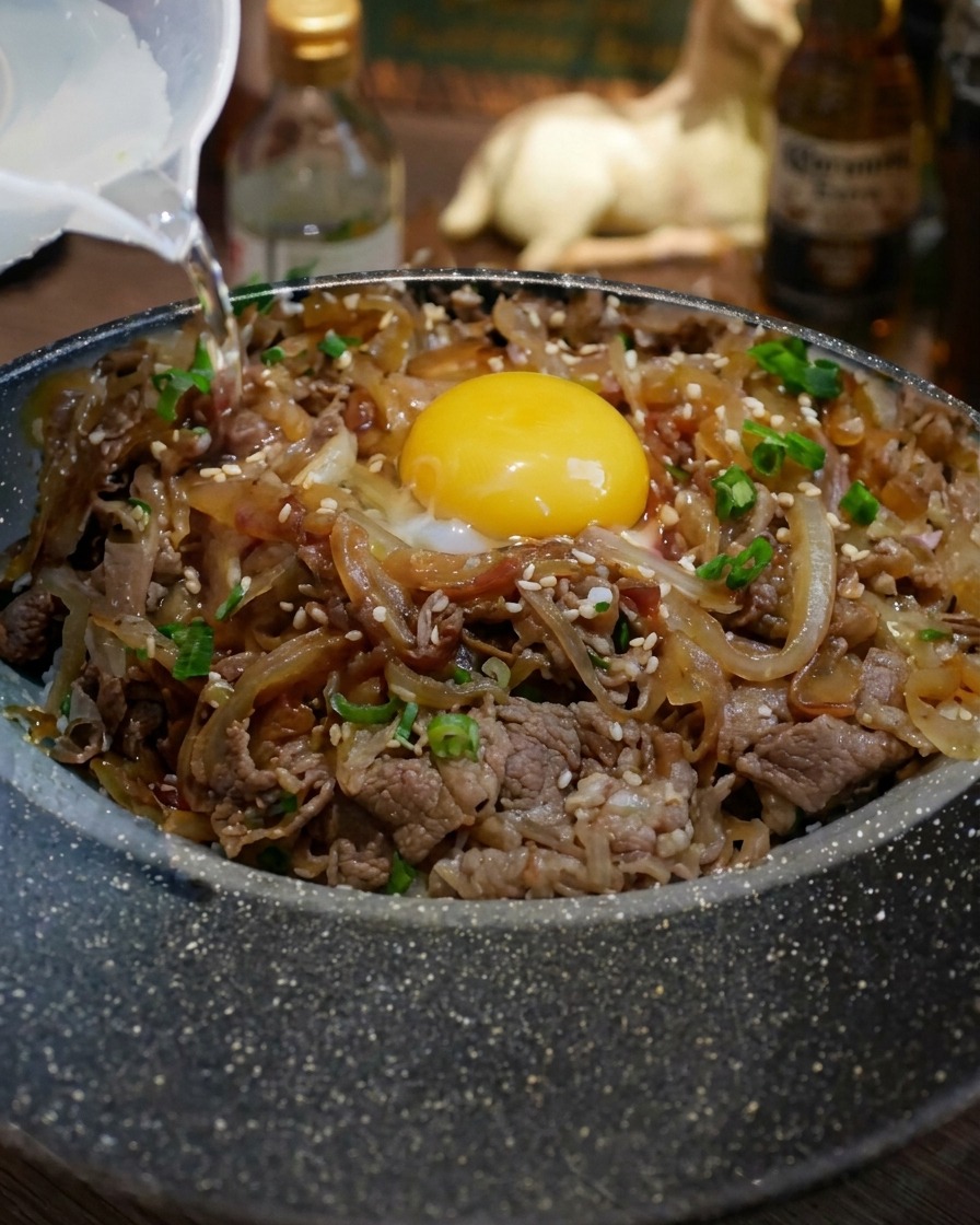 A small amount of water being poured into a black pan, preparing it for the beef.