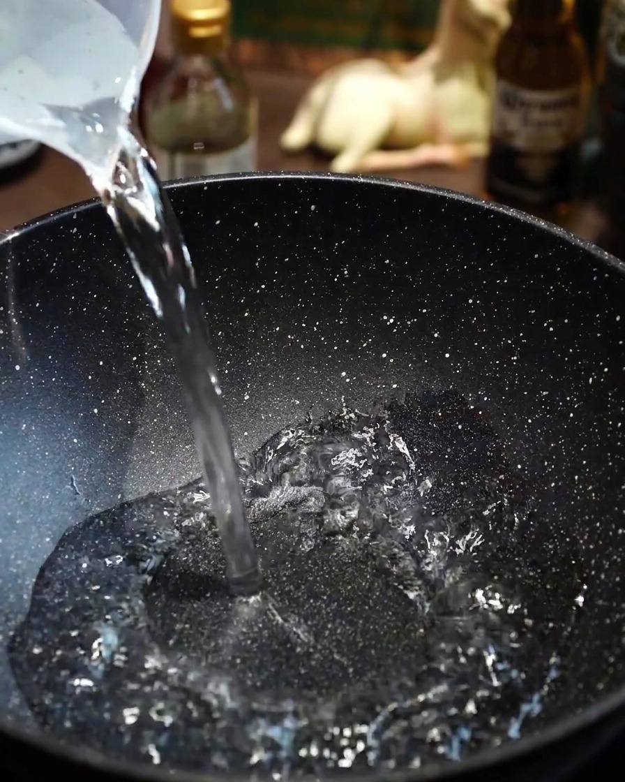 Thin slices of Wagyu beef being carefully added to boiling water in a pan.