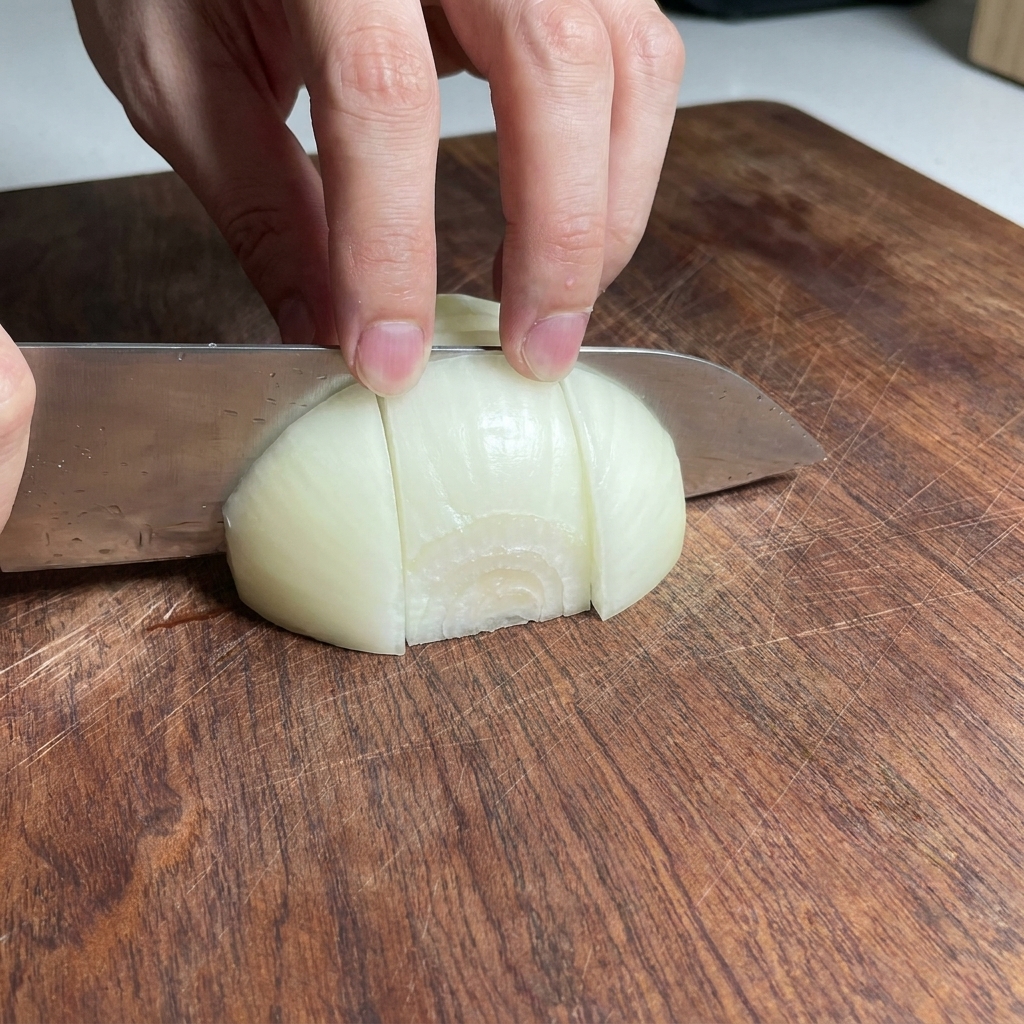Onion pieces chopped into chunks on a wooden cutting board.