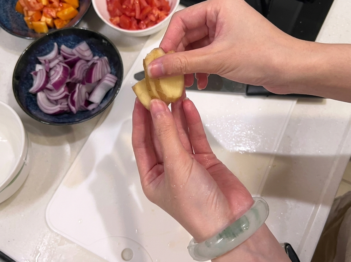 Beef being carefully sliced into equal cubes on a white plastic cutting board.