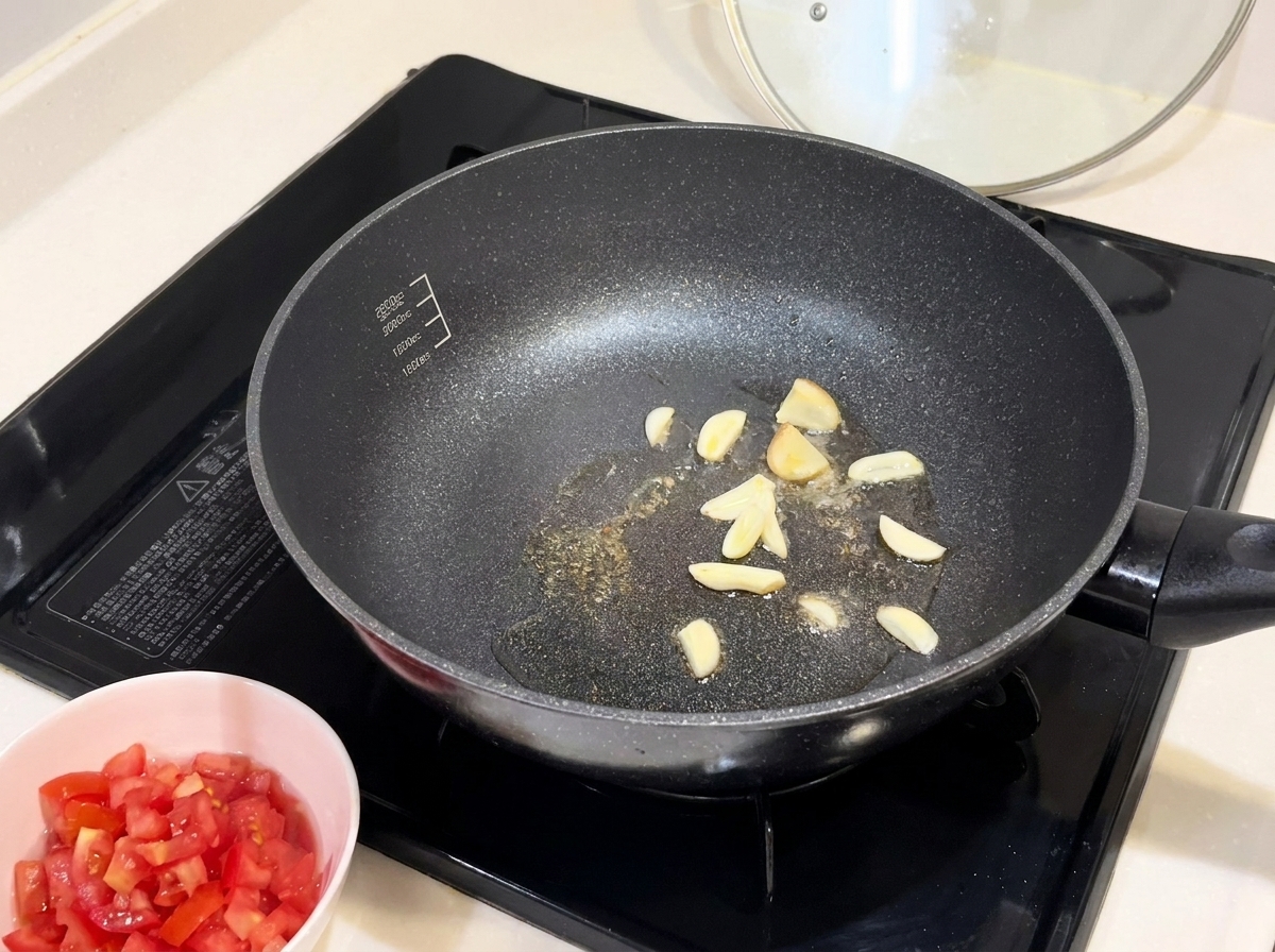 Golden slices of garlic frying in a hot, oiled pan.