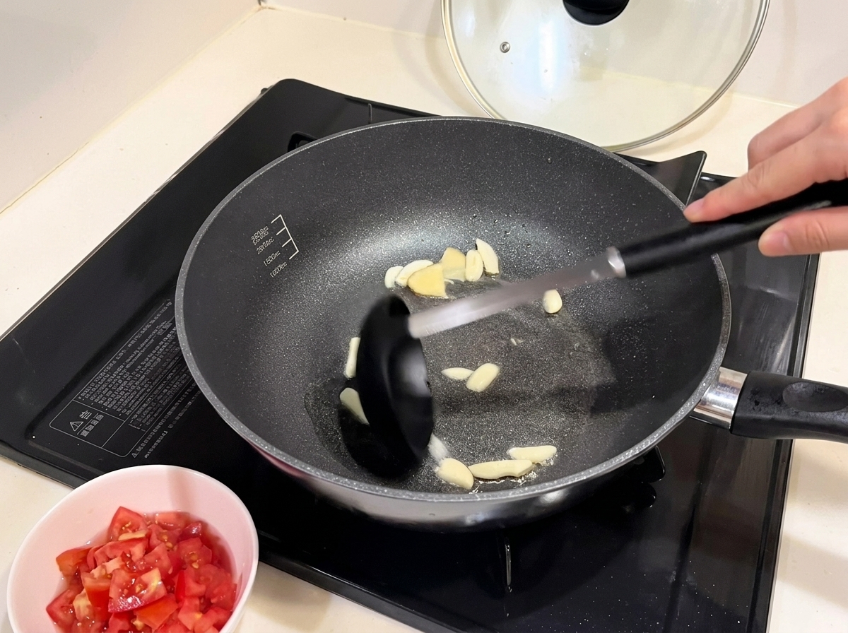 Red onion pieces softening in a pan with sautéed garlic.