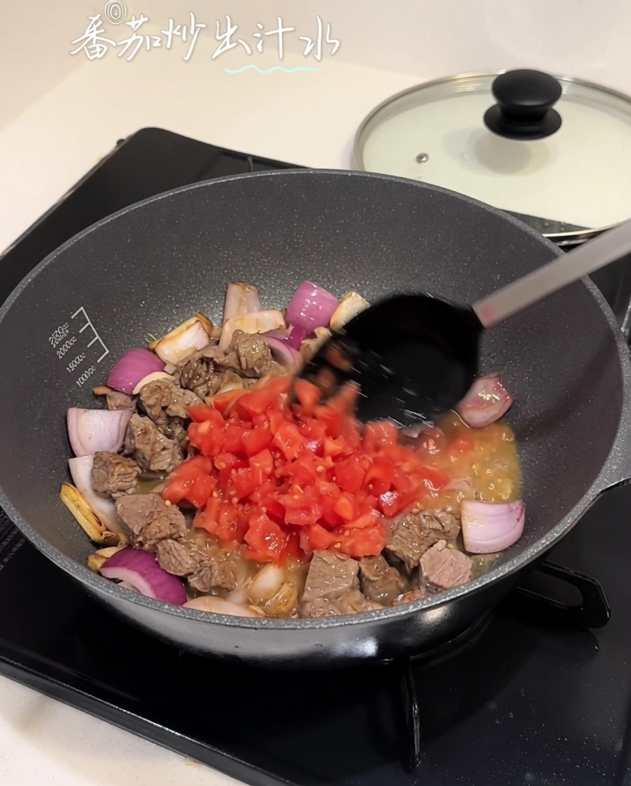Diced tomatoes being stirred into a beef and onion mixture in a pan.