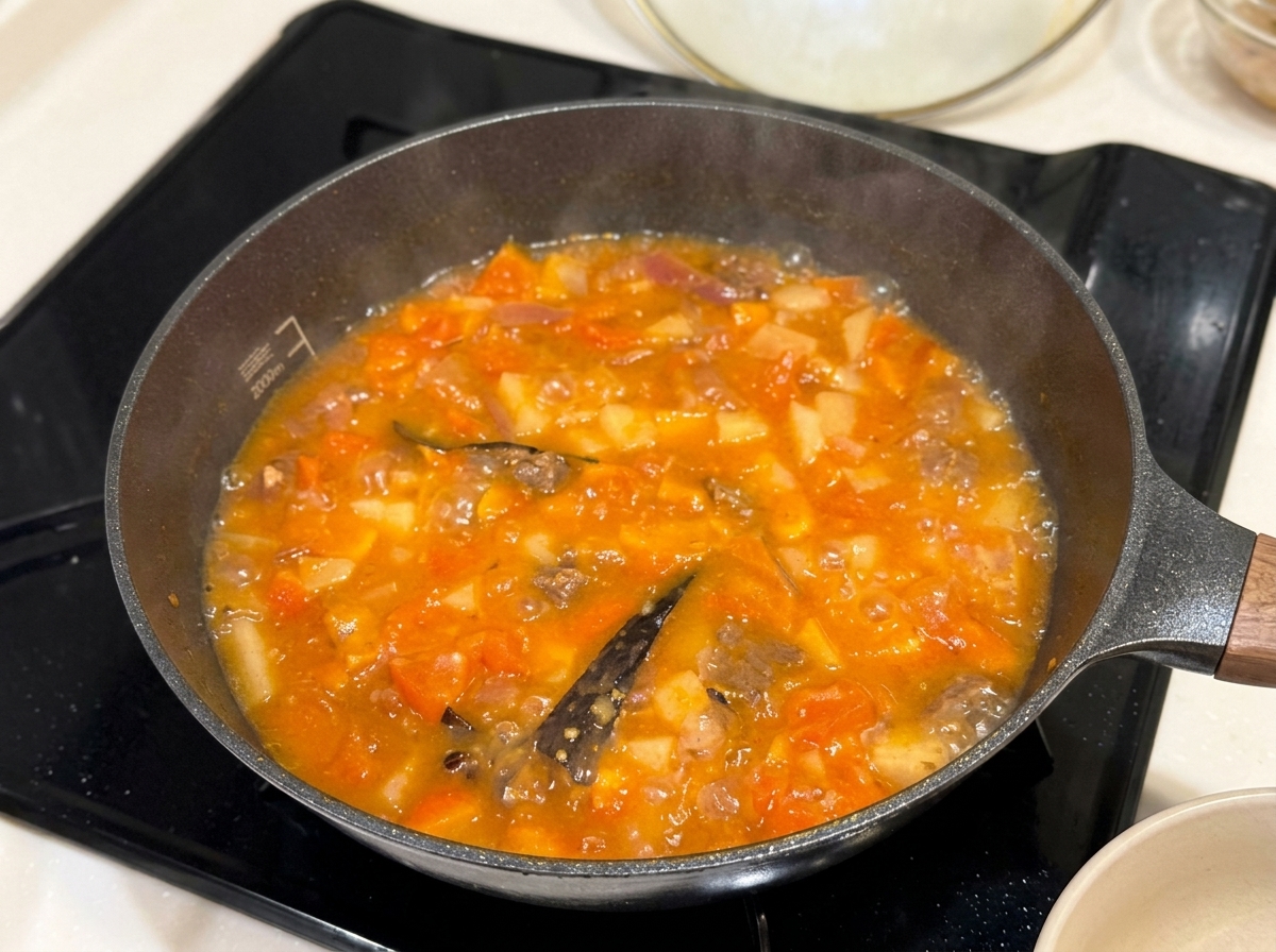 Solid curry seasoning blocks being placed into a pan of simmering stew.