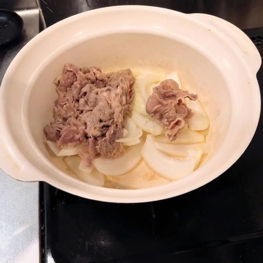 Blanched beef mixed with onions inside a cooking pot.