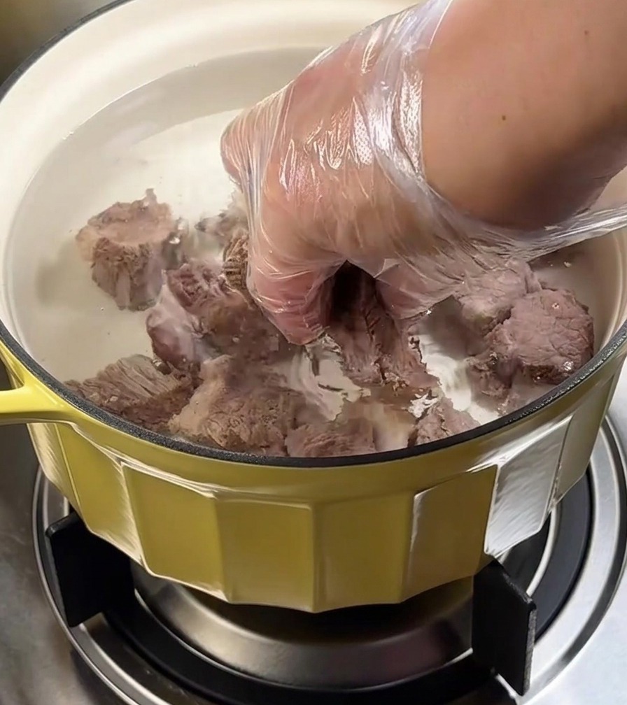 Pot of beef brisket simmering on the stove under a lid.