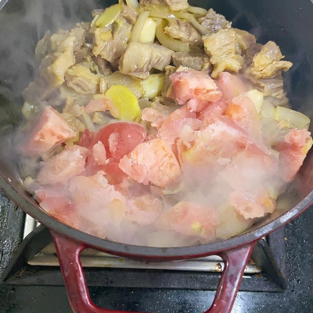 Adding frozen tomato pieces into the stir-fry pan.