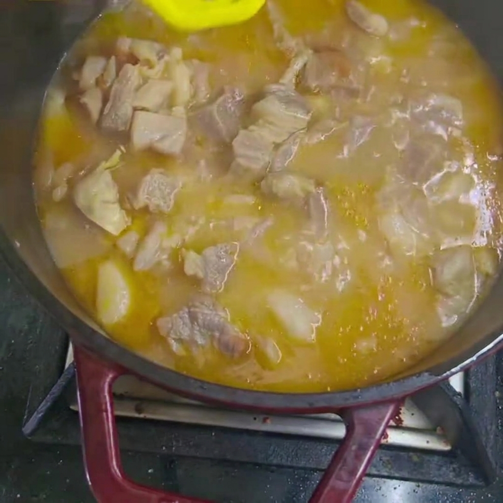 Carrot and potato chunks added to the simmering beef stew in the pot.