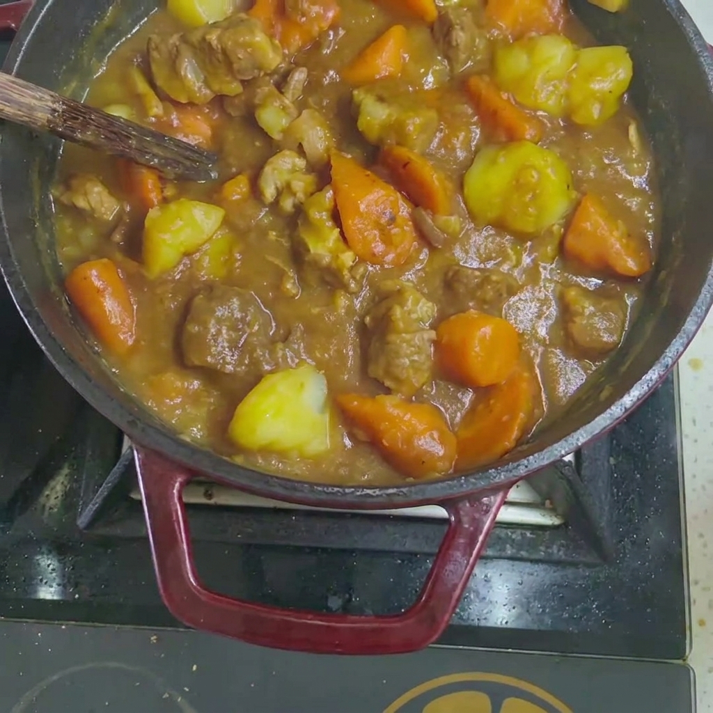 Solid curry cubes being dropped into the cooked beef and vegetable stew.