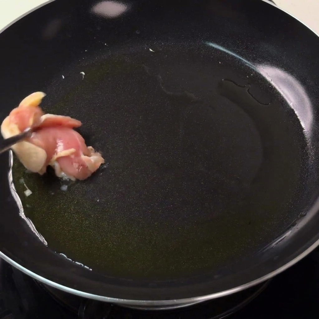 Chicken pieces searing in a hot pan with oil until golden brown.
