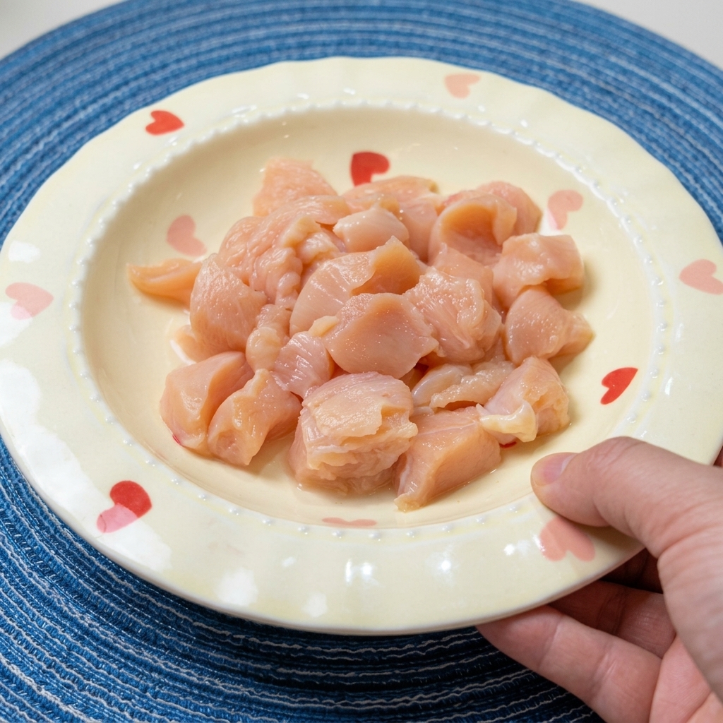 Diced raw chicken breast in a bowl, being seasoned with soy sauce, cooking wine, and spices.