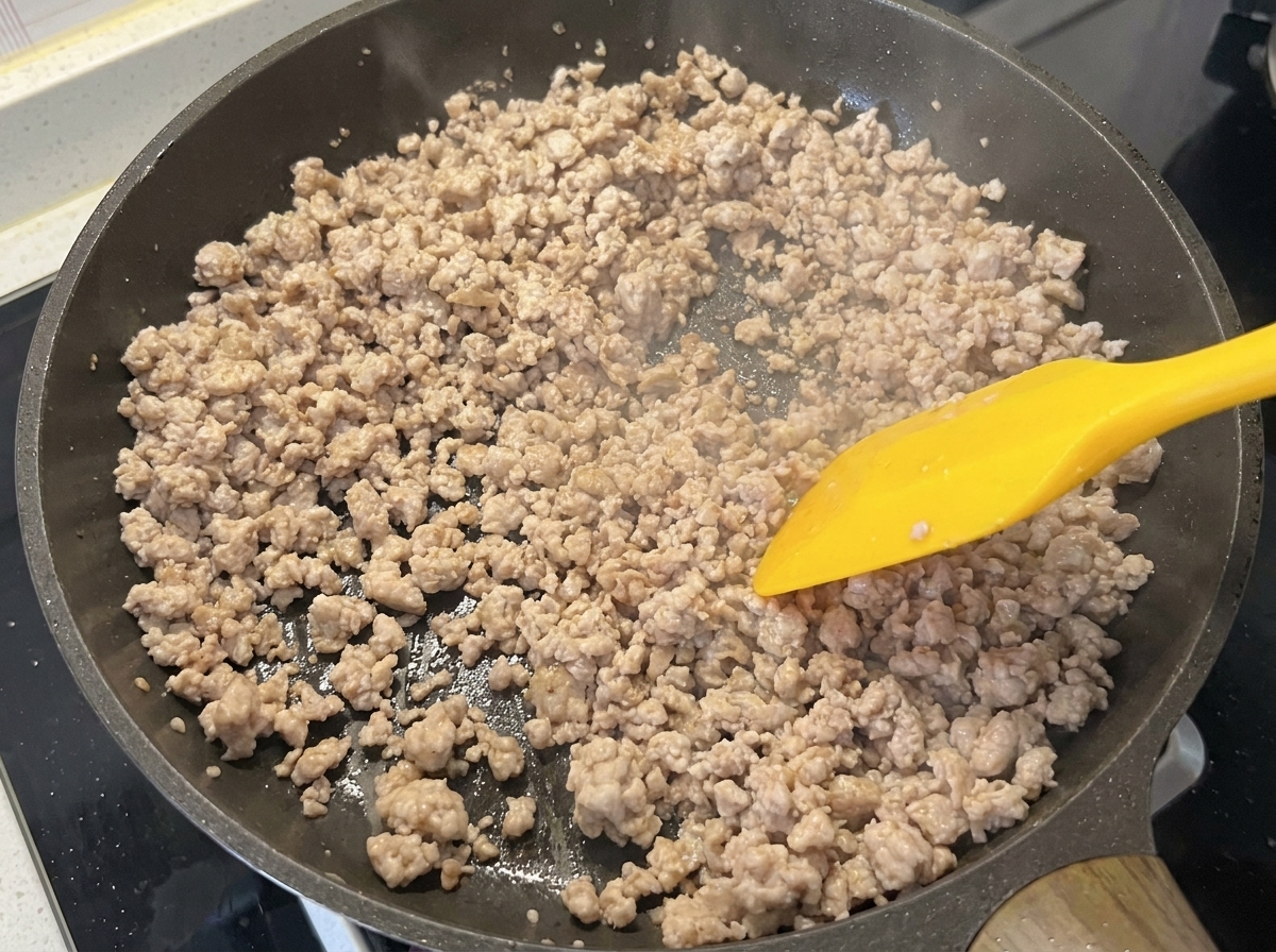 The minced pork in the pan, looking browned and dry after stir-frying.