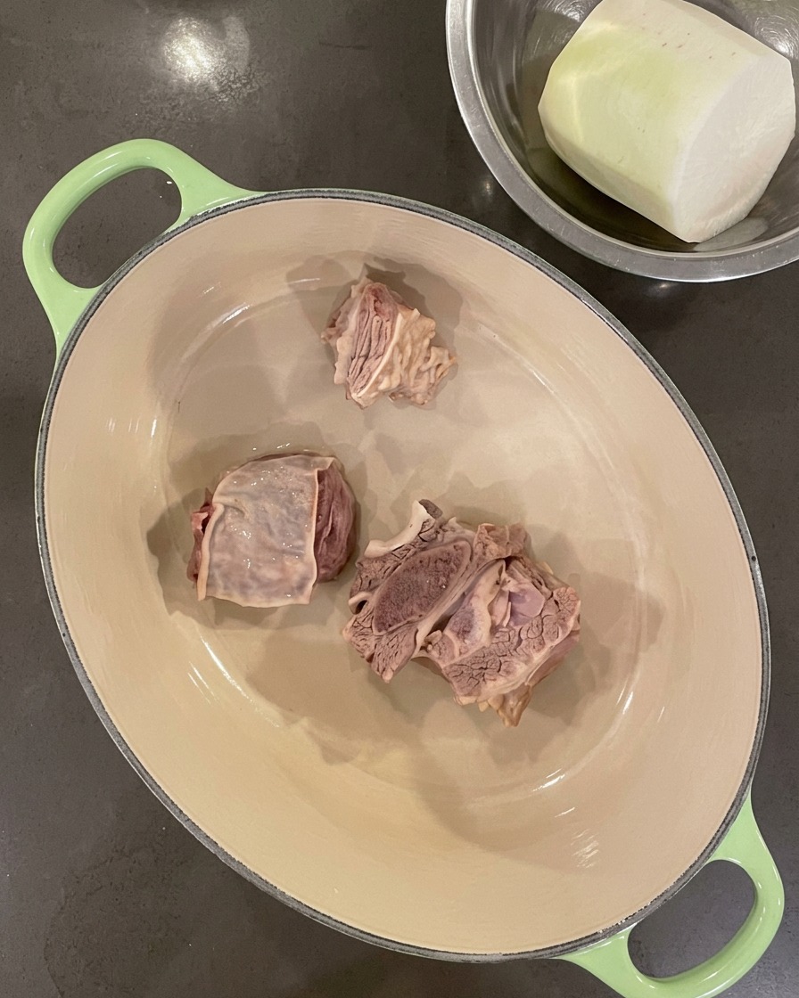Cleaned short ribs arranged at the bottom of an empty Dutch oven.