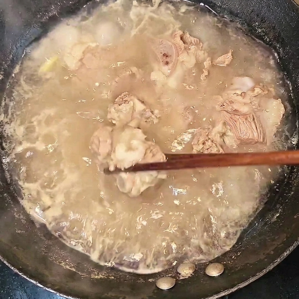 Blanched beef ribs being lifted out of the boiling water with chopsticks.